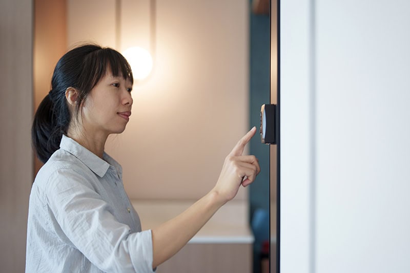 A women adjusting her thermostat.