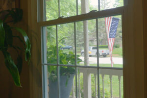 Video - Energy Saving Tip 5. Window during the daytime with American flag outside.