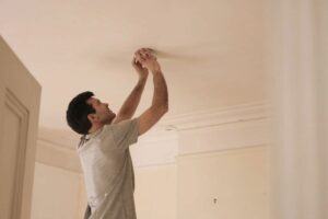 Image of someone fiddling with smoke detector. Video - When Do I Need to Replace the Batteries in My Smoke Detector?